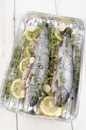 trout with lemon slices, thyme, crushed pepper and garlic  prepared  to grill