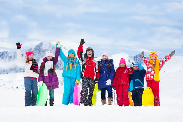 Row of large group of kids, friends, boys and girls standing together outside in snow and waiving hands
