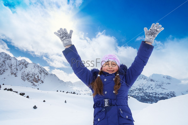 Close portrait of happy 8 years old Caucasian girl with\
lifted from excitement hands on snow outside in winter
