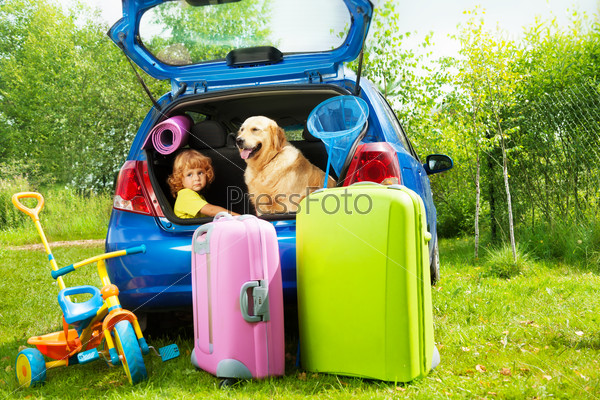 Close shoot of a car with retriever dog and three years old boy waiting in the trunk with bags for trip, trickle, ball, scoop-net