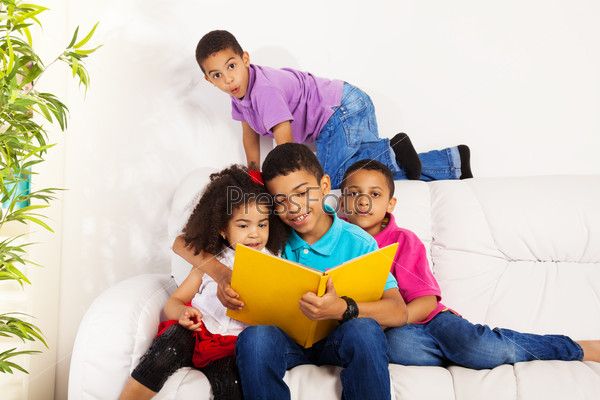Family, group of four kids with older brother reading books to brothers and sister