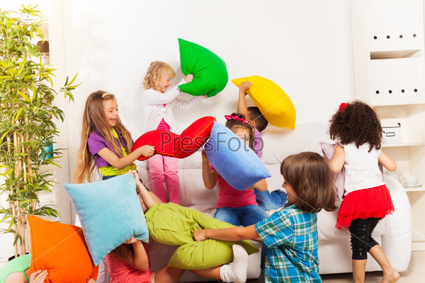 Pillow Fight - Large Group Of Kids Actively Playing With Pillow In The Living Room On The Coach
