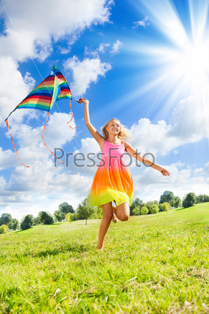 Happy 14 years old girl running in the field with big color kite