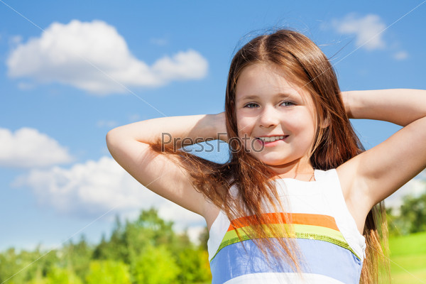 Close portrait of happy smiling little girl with long hairs standing outside on sunny day