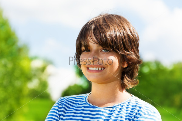Close portrait of 14 yeas old boy smiling, outside on sunny day
