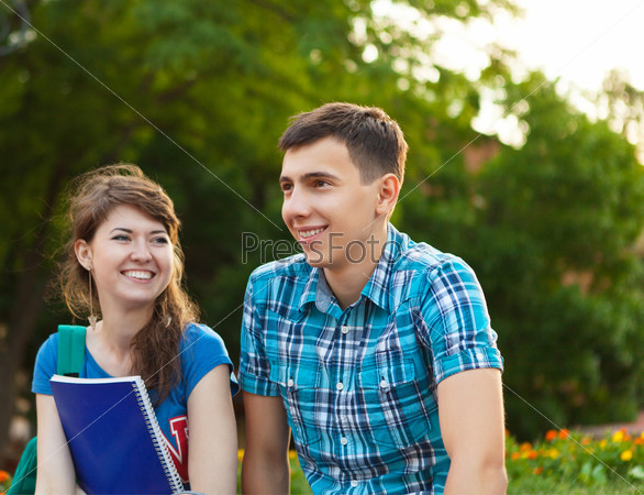 Two students or teenagers with notebooks outdoors in summer evening