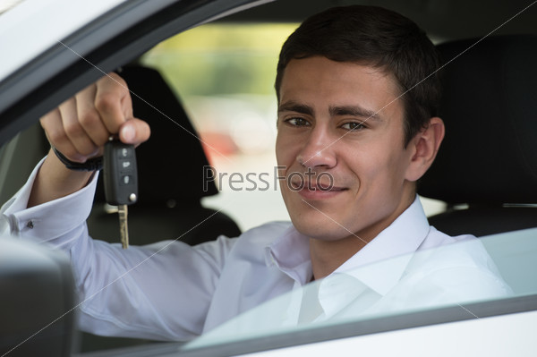 Happy vehicle buyer inside his new car with car key