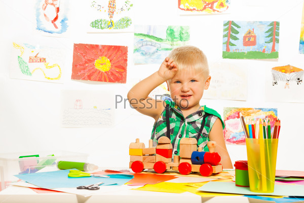 2 years old blond boy in the preschool art class  with pencils toys and blocks