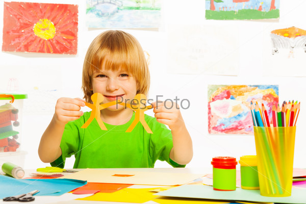 Happy 4 years old boy with paper garland on preschool art lesson