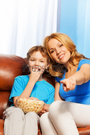 Happy mother pointing forward and son watch TV