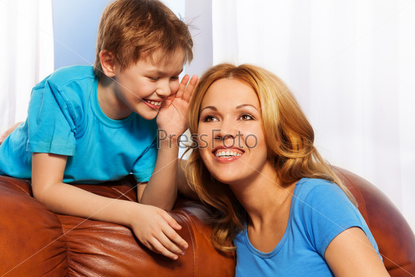Smiling boy whispering a secret to mother