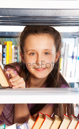 Smiling girl portrait through bookshelf