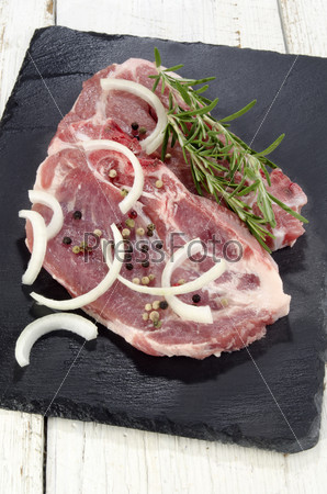 sliced Ã?Â¢??Ã?Â¢??pork shoulder with onions and rosemary on slate