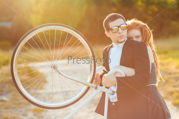 Young stylish guy with girl and the bicycle outdoors