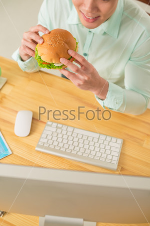 Office manager eating a hamburger, view from above