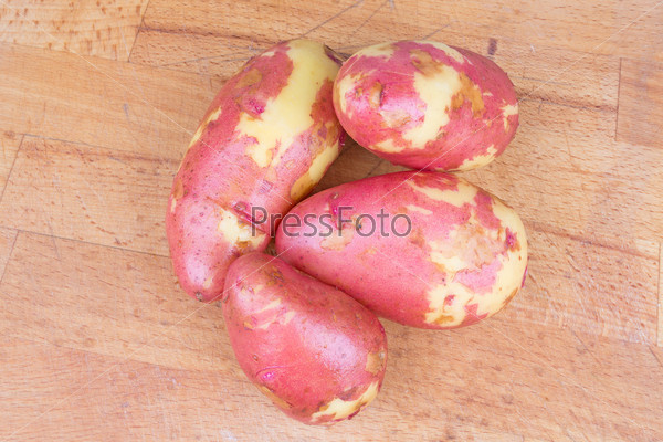 Big red potatoes on wooden table