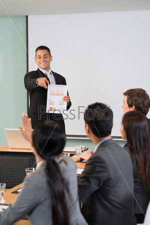Businessman pointing at the woman who is asking a question during the meeting