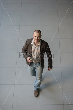 Attractive businessman using his smartphone in office building lobby. Top view
