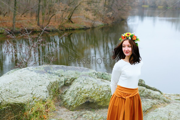 Young beautiful woman with flower wreath outdoors near the river