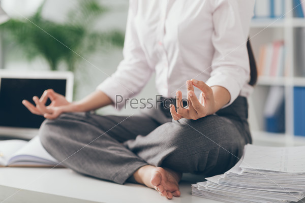 Cropped image of business woman practicing yoga in the office