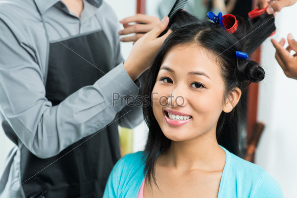 Beautiful woman having her hair curled in salon