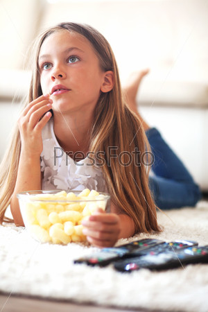 8 years old child watching tv laying down on a white carpet at home alone