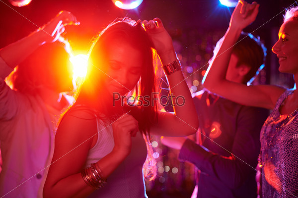 Pretty girls dancing in night club on background of guys