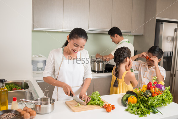 Parents cooking, while their children playing in the kitchen