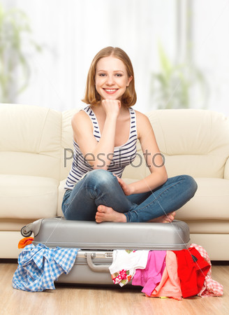 Happy woman is packing suitcase at home