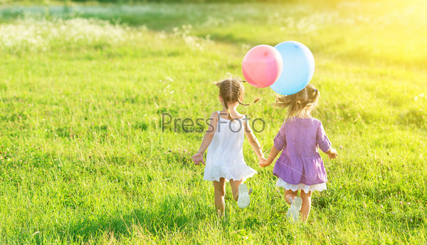 happy girls kids twin sisters with balloons in summer field on nature