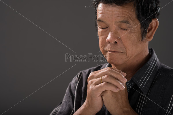 Senior man praying with his hands clasped