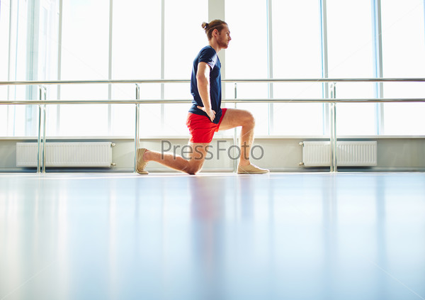 Handsome young man practicing physical exercise in gym