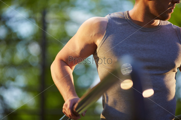 Sportsman in grey vest training on sport equipment outside