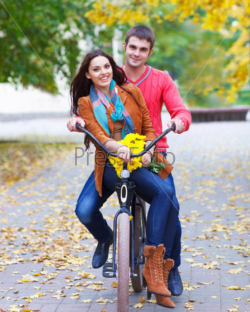 Счастливая пара с велосипедом в осеннем парке