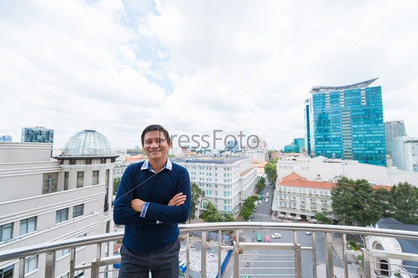 Portrait of cheerful businessman standing on a balcony overlooking the city