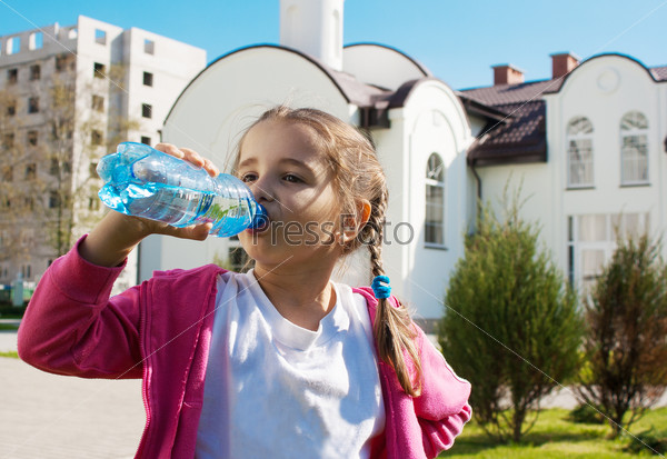 girl drinks water from a plastic bottle