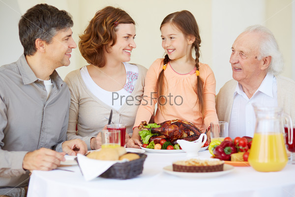 Portrait of happy family members looking at cute girl by Thanksgiving table