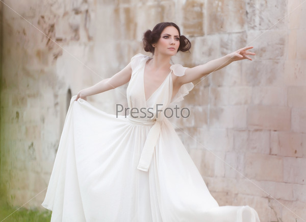 Lovely woman dressed in white long dress leaning forward in a very gracious, ballet like pose.