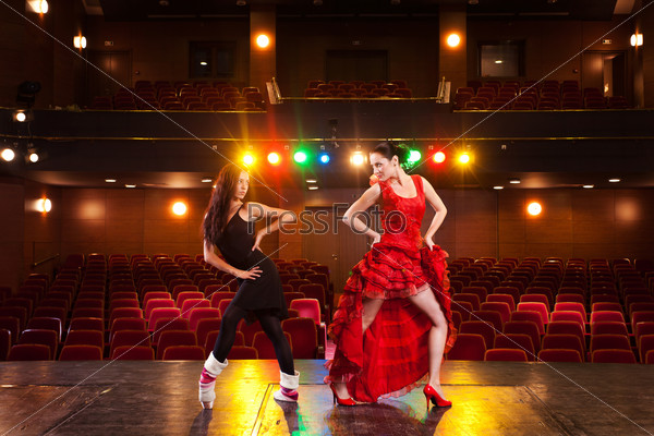Two beautiful feminine dancers with different dance styles, performing a duet on stage.