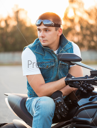 Biker man sitting on his motorcycle outdoors, stock photo