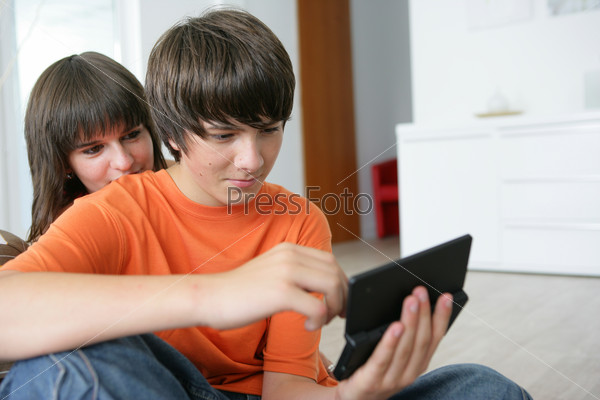 Portrait of a boy and a girl sitting on a cushion with a portable game console