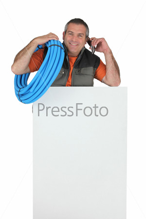 Electrician with roll of blue corrugated plastic tubing, a phone and a board left blank for your message