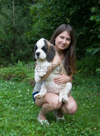 happy girl holding a puppy St. Bernard summer