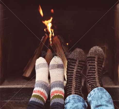 Close up of romantic legs of a couple in socks in front of fireplace at winter season at home