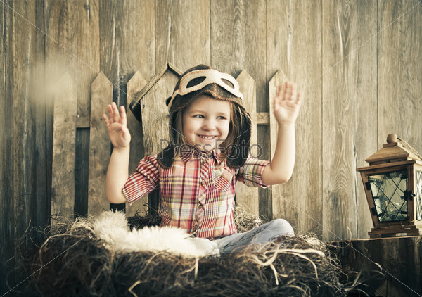 Happy kid playing in pilot helmet near the wooden background
