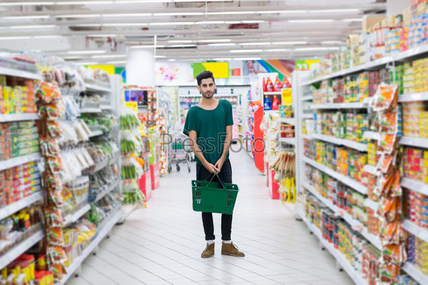 Full-length portrait of young Hispanic with basket man in a supermarket