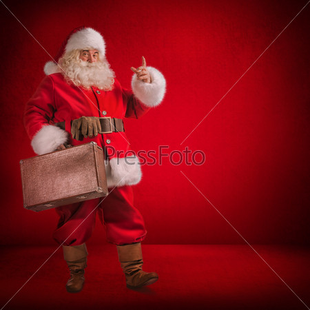 Christmas: Santa Claus Standing With Travel Bag with Gits on red background