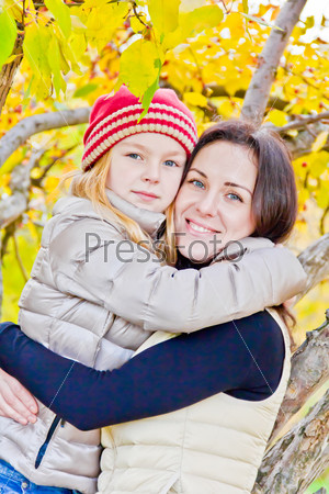 Photo of mother and daughter in autumn sitting on tree
