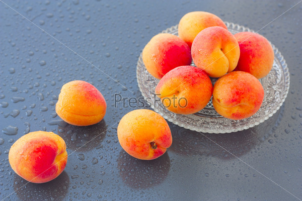 wet apricots on a plate on the wet background