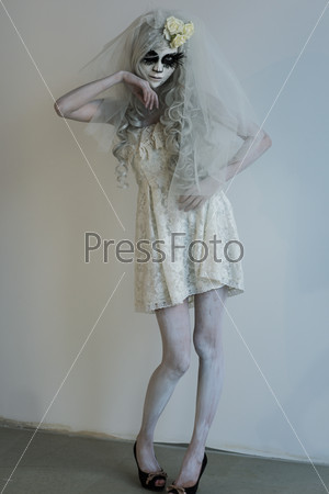 Halloween witch. Beautiful woman wearing santa muerte mask and wedding dress posing full length